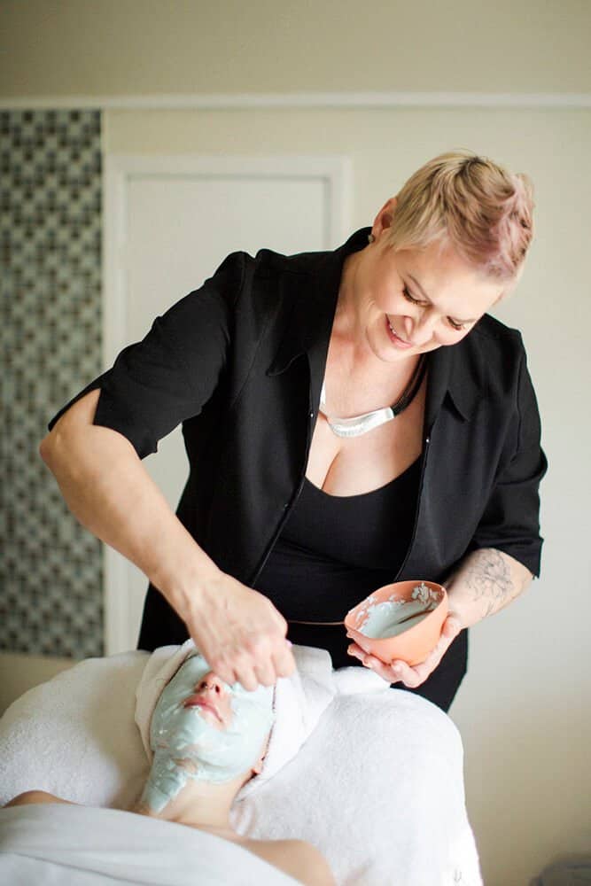 esthetician applying facial mask to woman